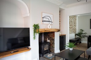 Charming living space with a rustic fireplace, modern decor, and a wall-mounted TV. Cozy and stylish.