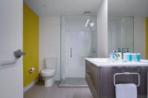 The bathroom has a glass shower, modern vanity and toilet.