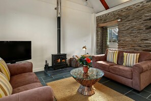Sofas, coffee table with flowers, TV and wood burner in the living area