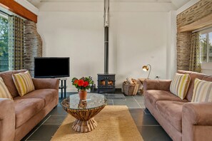 Sofas, coffee table with flowers, TV and wood burner in the living area