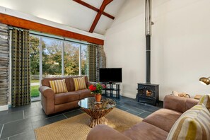 Sofas, coffee table with flowers, TV and wood burner in the living area