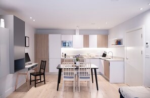 The fully equipped kitchen has an oven and induction hob, microwave, kettle, toaster, dishwasher, Nespresso machine, and a dining table with four chairs.