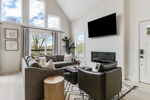 Lavish living room with seating for 6-8 people, 60" smart Roku TV, and electric fireplace. Easily walk out to the deck, too!
