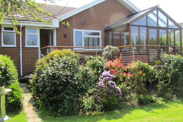 The view of The Anchorage from the garden with plants and shrubs