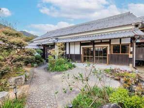 ・[Exterior] The entrance to the accommodation is on the left. Your stay begins on a stone-paved path surrounded by plants.
