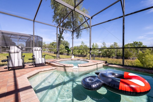 Back screened in patio with outdoor seating, grill, pool, and hot tub