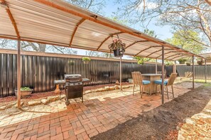 This covered back patio offers an excellent space for outdoor entertaining, featuring a BBQ grill and a cozy fireplace. Perfect for evening gatherings or enjoying a relaxing moment in nature, it’s a great spot to unwind.