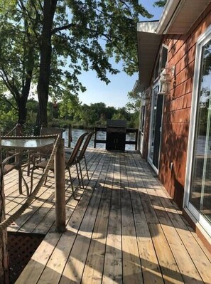 Deck full length of cottage with BBQ, glass table to dine or sit out