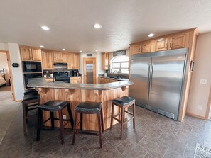 Stocked kitchen with commercial size refrigerator and bar seating