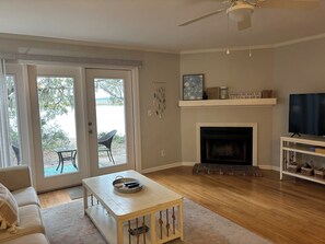 Living room with sofa, coffee table, & large screen TV. Fireplace not functional