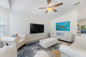 Navarre, FL: Luxurious modern white living room with 75" HDTV & local art.