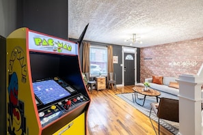 Envision a living room that harmoniously blends modern comfort with a touch of nostalgia, featuring a classic Pac-Man arcade machine.