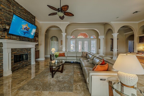 Living Elegance - - Relax in this cozy yet sophisticated living room, featuring plush seating and a warm fireplace
- Admire the elegant arched columns and natural stone accents that elevate the space
- Perfect for movie nights, family gatherings, or unwinding in style