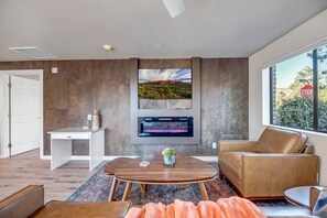 Living area with leather sofa, smart TV, and electric fireplace