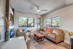 Living area with leather sofa, smart TV, and electric fireplace