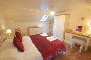 Tal y Gaer Cottage kingsize bedroom with white wardrobe, chest of drawers and dressing table