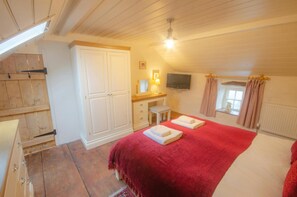 Tal y Gaer Cottage kingsize bed with red throw and white towels on bed