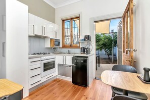 The charming compact kitchen corner has everything needed for home cooking such as a single-drawer dishwasher, oven, stovetop and range hood, mini fridge and a coffee machine. 
