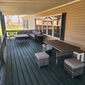 Large covered front porch with comfortable seating and dining areas.