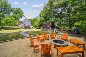 The fire pit is next to the river and in the center of a sand area making it feel like a little beach.