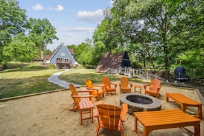The fire pit is next to the river and in the center of a sand area making it feel like a little beach.