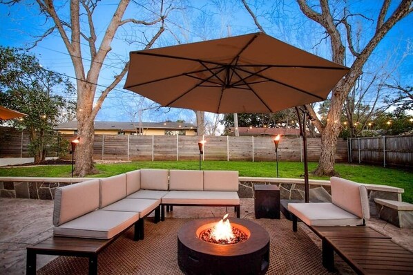 Discover your private backyard haven: cozy firepit, ambient tiki torches, and plush seating. Picture-perfect moments await, grill included but just out of shot.