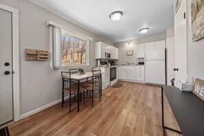 A modern kitchen seamlessly integrated with a dining area featuring a sleek table, designed to comfortably accommodate four guests for intimate meals and conversations.
