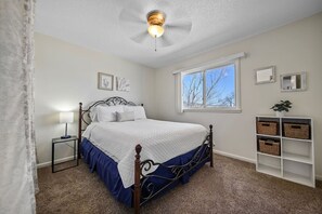 Comfortable queen bed complemented by a bedside lamp, creating a cozy and functional sleeping space for restful nights.