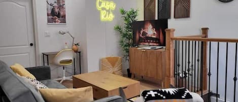 The main living area, with sofabed, coffee table, SmartTV, office desk and neon.