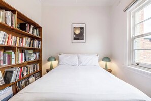 The second bedroom features a cosy double bed framed by funky sage dome-shaped lamps. The bedroom has an impressive library collection that is perfect for quiet moments with a good read.