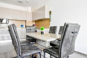 Then, invite them to a dining and kitchen area where they can savor meals or share a coffee, the contemporary table surrounded by plush chairs stands ready for dining or a productive work session, while the kitchen, with its state-of-the-art appliances, beckons the culinary enthusiast or the quick meal planner.