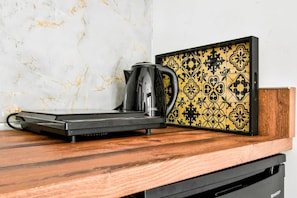 Morning essentials: sleek hotplate and kettle set against marbled elegance.