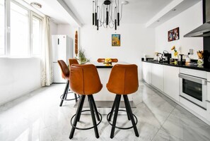 Elegant dining area with trendy pendant lights above a sleek black table, flanked by stylish leather bar chairs.