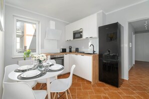  Open-concept kitchen and dining area with a small dining table set for two and a refrigerator in the background.