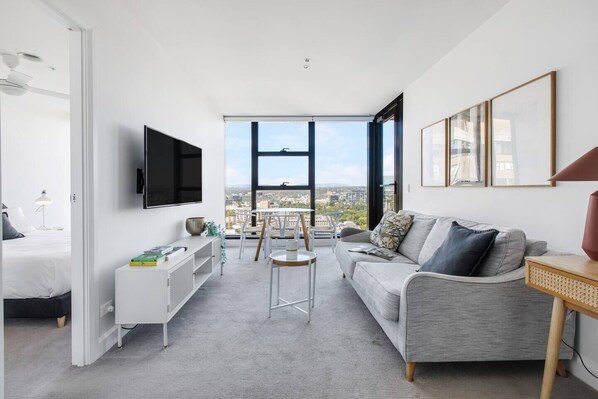 The living area is cosy and welcoming with a soft lounge sitting across from a large wall-mounted HD TV. 
