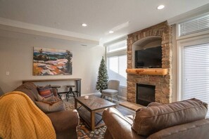 Experience the cozy living room, outfitted with plush seating, an expansive smart TV, and sliding doors that frame the breathtaking mountain vistas.
