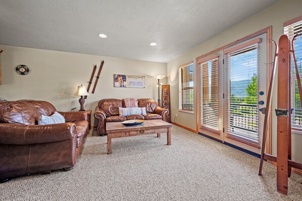 Experience the cozy living room, outfitted with plush seating, an expansive smart TV, a fireplace and patio doors that frame the breathtaking mountain vistas.