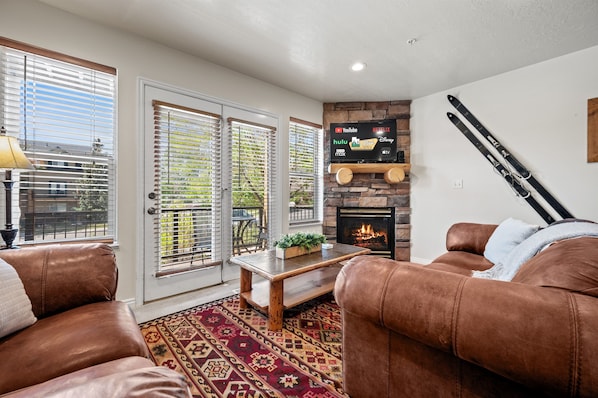 Experience the cozy living room, outfitted with plush seating, a fireplace, an expansive smart TV, with access to the deck..