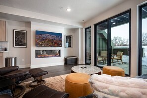 Experience the cozy living room, outfitted with plush seating, a fireplace, an expansive smart TV, and patio doors that frame the breathtaking mountain vistas.
