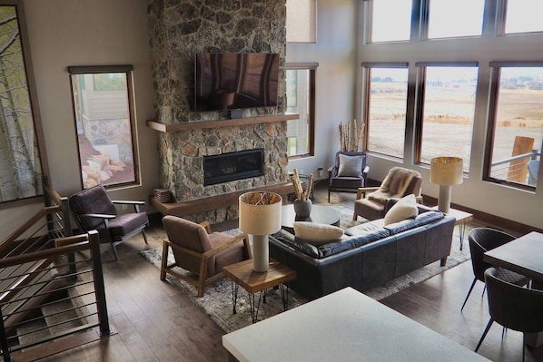 Experience the cozy living room, outfitted with plush seating, a fireplace, an expansive smart TV, and sliding patio doors that frame the breathtaking mountain vistas.