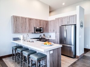 The gourmet kitchen features breakfast bar with seating for four and is equipped with stainless steel appliances, including a microwave, gas stove, and spacious refrigerator.