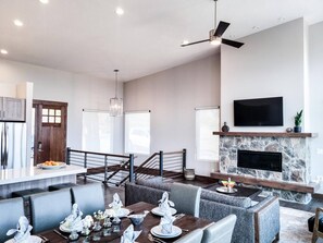 Experience the cozy living room, outfitted with plush seating, a fireplace, an expansive smart TV, and patio doors that frame the breathtaking mountain vistas.