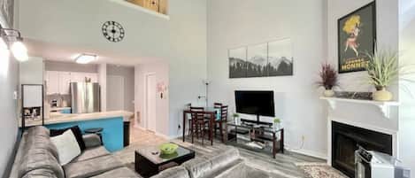 Experience the cozy living room, outfitted with plush seating, a fireplace, an expansive smart TV, and windows that frame the views of the great outdoors.