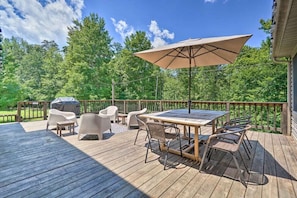 Enjoy serene woodland scenery on our spacious deck, equipped with a shaded dining area, grill, and cozy lounge chairs, ideal for outdoor dining or simply soaking up the peaceful surroundings.