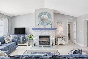 Spacious and light filled living room with multiple sofas, vaulted ceilings, and a large flat screen TV