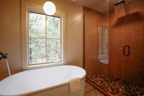 Primary Bath with a beautiful rain shower and soaking tub featuring artisanal bath soap and salts from Michigan made soap company Soap Shed