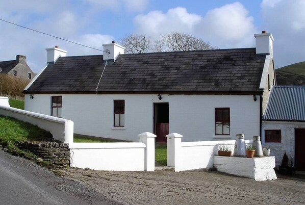 Front side view of cottage. Garden enclosed with a wall.
