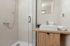 Beige bathroom with a shower, toilet, washbasin and mirror.