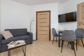 Living area with sofa bed, dining area and TV.