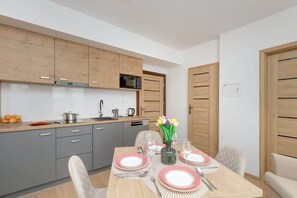 Dining table with tableware and kitchenette.